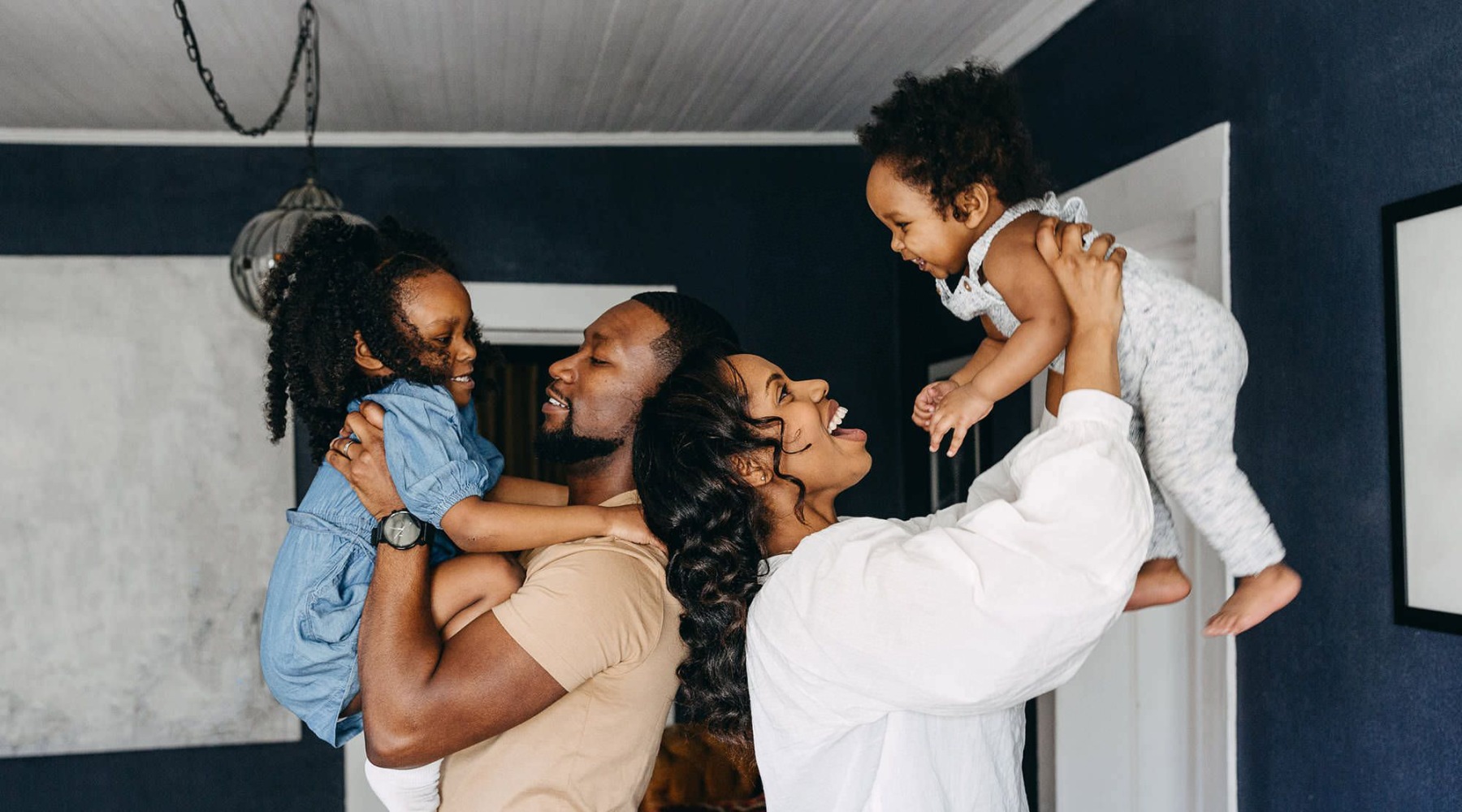 young parents hold up their children in room